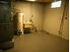 Basement utility area featuring a water heater and utility sink with painted floors and block walls at 1106 N Hartman Dr, Indianapolis, IN 46219