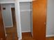 Bedroom closet featuring wood door with shelving, and hardwood floors with natural light from the hallway at 1106 N Hartman Dr, Indianapolis, IN 46219