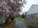 View of the home's exterior with stone and a blooming tree and long driveway at 1106 N Hartman Dr, Indianapolis, IN 46219