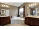 A bathroom featuring a large tub with a window, double sinks, and dark wood cabinets at 11629 Boothbay Ln, Fishers, IN 46037