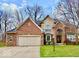 Traditional brick home with a well-manicured lawn, two-car garage, arched entryway, and mature landscaping at 12441 Bent Oak Ln, Indianapolis, IN 46236