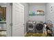 Well-equipped laundry room with a modern washer, dryer, storage shelf, and ample space at 1436 Amberwoods Ct, Indianapolis, IN 46239