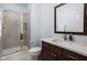 Modern bathroom features a glass-enclosed shower, neutral tile, and vanity with a large mirror at 15250 Mooring E Cir, Carmel, IN 46033