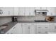 Updated kitchen featuring white cabinets, gray countertops, backsplash, and stainless steel appliances at 15250 Mooring E Cir, Carmel, IN 46033