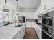Modern white kitchen with stainless steel appliances, stone countertops and hardwood floors at 15250 Mooring E Cir, Carmel, IN 46033