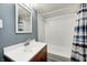 Bathroom with a mirror, wooden vanity and cabinet, and blue-stripped shower curtain at 156 S Cross St, Clayton, IN 46118