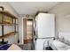 Functional laundry room featuring a stacked washer/dryer, sink, rustic shelving, and access to the bathroom at 2025 State Road 47, Lebanon, IN 46052
