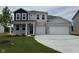 Inviting two-story home featuring a brick facade, a two-car garage, and a well-manicured lawn at 211 Ames Dr, Whiteland, IN 46184
