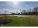 Backyard view with a serene pond surrounded by lush greenery and trees at 4034 Saddle Club S Pkwy, Bargersville, IN 46106
