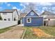 View of a blue house with a brown roof, surrounded by a white fence and unlandscaped yard at 555 N Hamilton Ave, Indianapolis, IN 46201