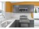 This updated kitchen features stainless steel appliances, quartz countertops, and gray cabinetry at 555 N Hamilton Ave, Indianapolis, IN 46201