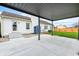 View of a concrete patio under a pergola, adjacent to a white home with a backyard, small blue storage shed, and a glass door at 6036 Terrytown Pkwy, Indianapolis, IN 46254
