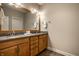 Bathroom featuring double sinks, granite countertops, wood cabinets, and a large mirror, offering a functional and elegant space at 768 Trailside Dr, Carmel, IN 46032