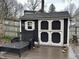 Backyard storage shed with a sliding barn door, sun emblem, and an adjacent lounge chair on a brick pad at 8224 Claridge Rd, Indianapolis, IN 46260