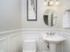A minimalist bathroom featuring a pedestal sink, a white toilet, and decorative wainscoting for a clean look at 9880 Wading Crane Ave, Fishers, IN 46055