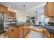 A kitchen that opens to the dining room, featuring wooden cabinets, an island with seating, and stainless steel appliances at 9880 Wading Crane Ave, Fishers, IN 46055