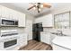 Functional kitchen features white appliances and cabinets, black refrigerator, stainless sink, and wood grain flooring at 10944 Echo Trl, Indianapolis, IN 46236