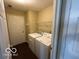 A bright laundry room with a washing machine and dryer next to a door at 11876 Wapiti Way, Noblesville, IN 46060