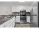 Kitchen with white cabinets, stainless steel appliances, dark countertops, and wood-look flooring at 1512 Tipton Ln, Columbus, IN 47201