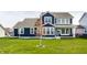 Expansive backyard view with a well-manicured lawn, young trees, and the rear of a charming two-story home at 15679 Woodford Dr, Westfield, IN 46074