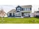 Beautiful backyard showcasing a lush lawn, young trees, and the back of a stunning two-story home with a covered patio at 15679 Woodford Dr, Westfield, IN 46074