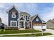 Charming two-story home with a well-manicured lawn, blue siding, white trim, and a pergola above the garage at 15679 Woodford Dr, Westfield, IN 46074