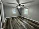 Empty bedroom with wood-look floors, neutral walls, natural lighting from windows, and a ceiling fan at 1627 E 8Th St, Anderson, IN 46012