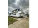 View of the home with a covered porch and detached garage, offering ample parking space at 1627 E 8Th St, Anderson, IN 46012