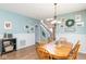 Dining room with hardwood floors, light blue walls with white trim, bright lighting, and an attached kitchen at 16963 Southall Dr, Westfield, IN 46074