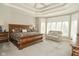 Main bedroom showcasing a decorative tray ceiling, large bed, and sitting area with bright windows at 2004 Caledonian Ct, Greenwood, IN 46143