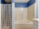 Neat bathroom featuring a tub with a blue patterned shower curtain and white tile walls at 20107 Marie Ct, Noblesville, IN 46062