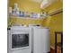 Bright laundry room has a yellow accent wall, overhead shelving, and a washer and dryer at 203 Winslow Dr, Westfield, IN 46074