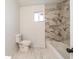 Updated bathroom featuring marble tile, toilet, tub and window at 2134 Dawson St, Indianapolis, IN 46203