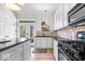 Well-lit kitchen boasts stainless appliances, stone backsplash, black countertops, and wood flooring at 2349 N Delaware St, Indianapolis, IN 46205