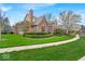 Attractive brick home with a neatly landscaped yard, including green grass, mature trees, and a paved sidewalk at 328 Millridge Dr, Indianapolis, IN 46290