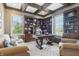 A home office features a coffered ceiling, built-in shelves, a desk, and comfortable seating at 4429 Serengeti Cir, Carmel, IN 46074