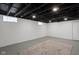 Unfinished basement showcasing painted concrete walls, exposed ceiling with glass block windows providing potential for customization at 6158 Ralston Ave, Indianapolis, IN 46220