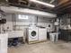 Basement laundry room with updated washer, dryer, and utilitarian sink at 645 N Ritter Ave, Indianapolis, IN 46219