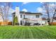 Expansive backyard showing manicured lawn, back exterior of the home, deck with outdoor furniture, and an umbrella at 8107 Parcrest Ct, Indianapolis, IN 46259