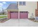 Two-car garage with dark red doors, exterior brick accents, and concrete driveway at 8414 Anchorage Ct, Indianapolis, IN 46236