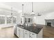 Open kitchen with island, modern lighting, hardwood floors, and view to a living room at 11172 Cliffside Dr, Fortville, IN 46040