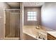 Bright bathroom featuring a corner bathtub, a window, and a glass-enclosed shower at 1228 Knapps Ct, Greenwood, IN 46142