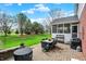 Landscaped backyard with a brick patio featuring a dining set and a view of the lush lawn and trees at 13225 Snow Owl Dr, Carmel, IN 46033