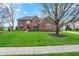 Stunning two-story brick home featuring a lush green lawn, mature trees, and a charming entryway at 13225 Snow Owl Dr, Carmel, IN 46033