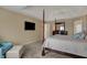 Well lit main bedroom with wall mounted tv, four poster bed and accent chair at 13225 Snow Owl Dr, Carmel, IN 46033