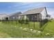 Well-maintained fenced backyard featuring a screened-in porch, manicured lawn, and young evergreen trees at 15755 Scher Dr, Westfield, IN 46074