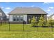 Back exterior view with a screened in porch, an iron fence, and young evergreen trees in the manicured backyard at 15755 Scher Dr, Westfield, IN 46074