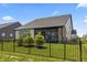 Back exterior view with a screened in porch, an iron fence, and young evergreen trees in the manicured backyard at 15755 Scher Dr, Westfield, IN 46074