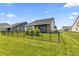 Back exterior view with a screened in porch, an iron fence, and young evergreen trees in the manicured backyard at 15755 Scher Dr, Westfield, IN 46074