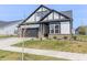 Attractive home with gray siding, black trim, a well-manicured lawn, and a freshly planted tree at 15755 Scher Dr, Westfield, IN 46074